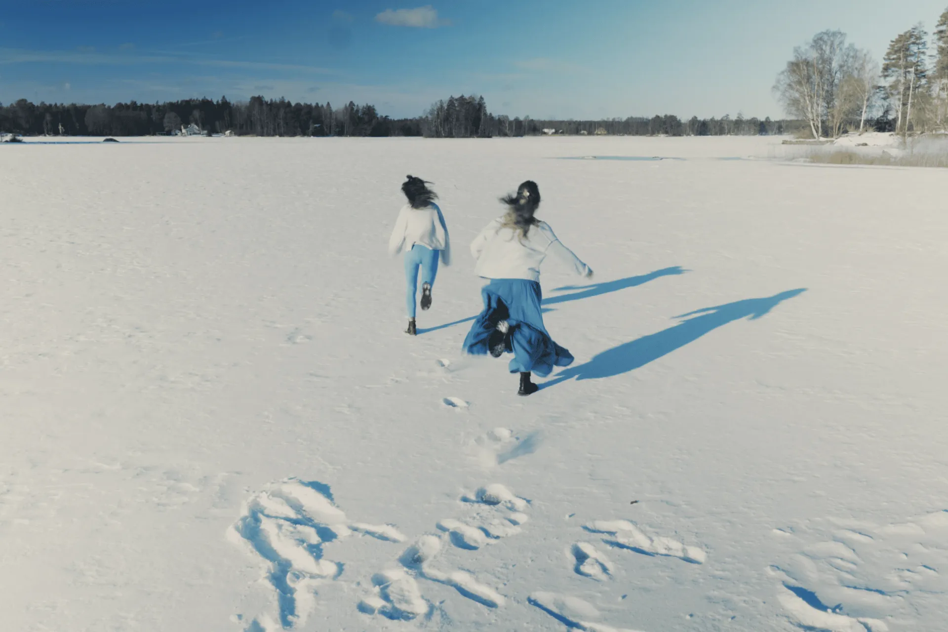 två kvinnor springer över en sjö full med snö i blekinge på en vinter retreat