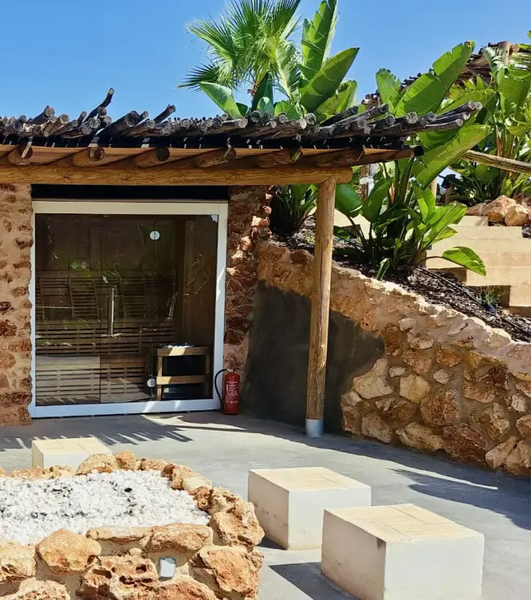 Entré med glasdörr, träpergola och stenmurar omgiven av palmer och tropiska växter i Algarve.