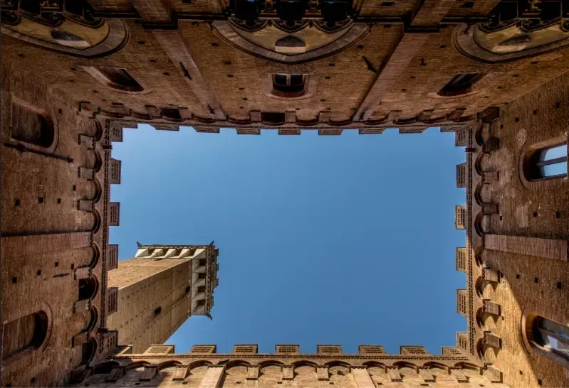 Historisk innergård med medeltida arkitektur och utsikt mot torn i Siena i Toscana