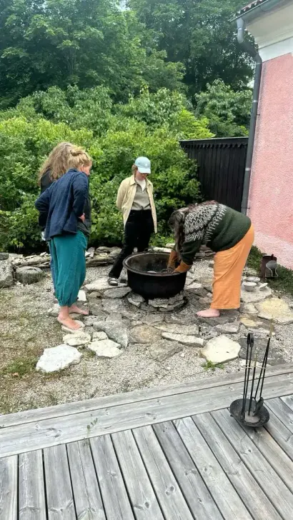 Deltagare samlade runt eld i naturnära retreatmiljö på Gotland