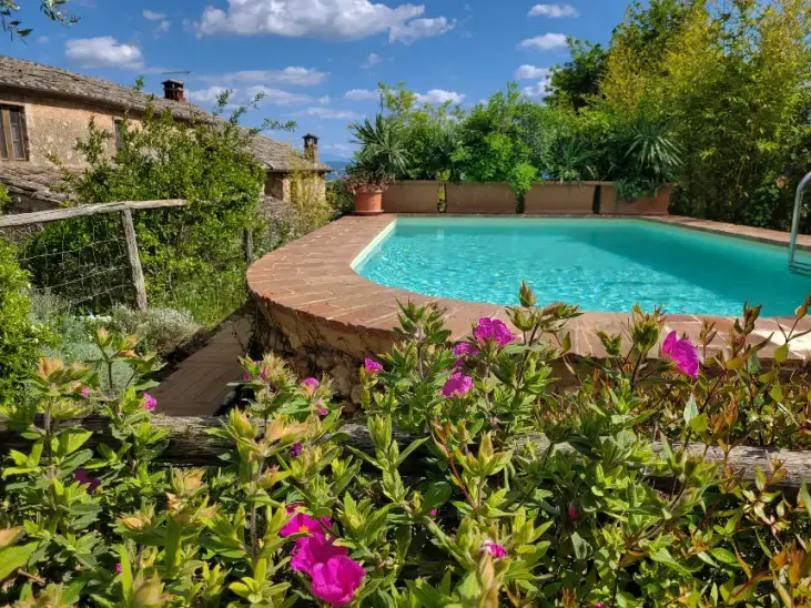 Pool och trädgård vid italiensk lantgård i Toscana