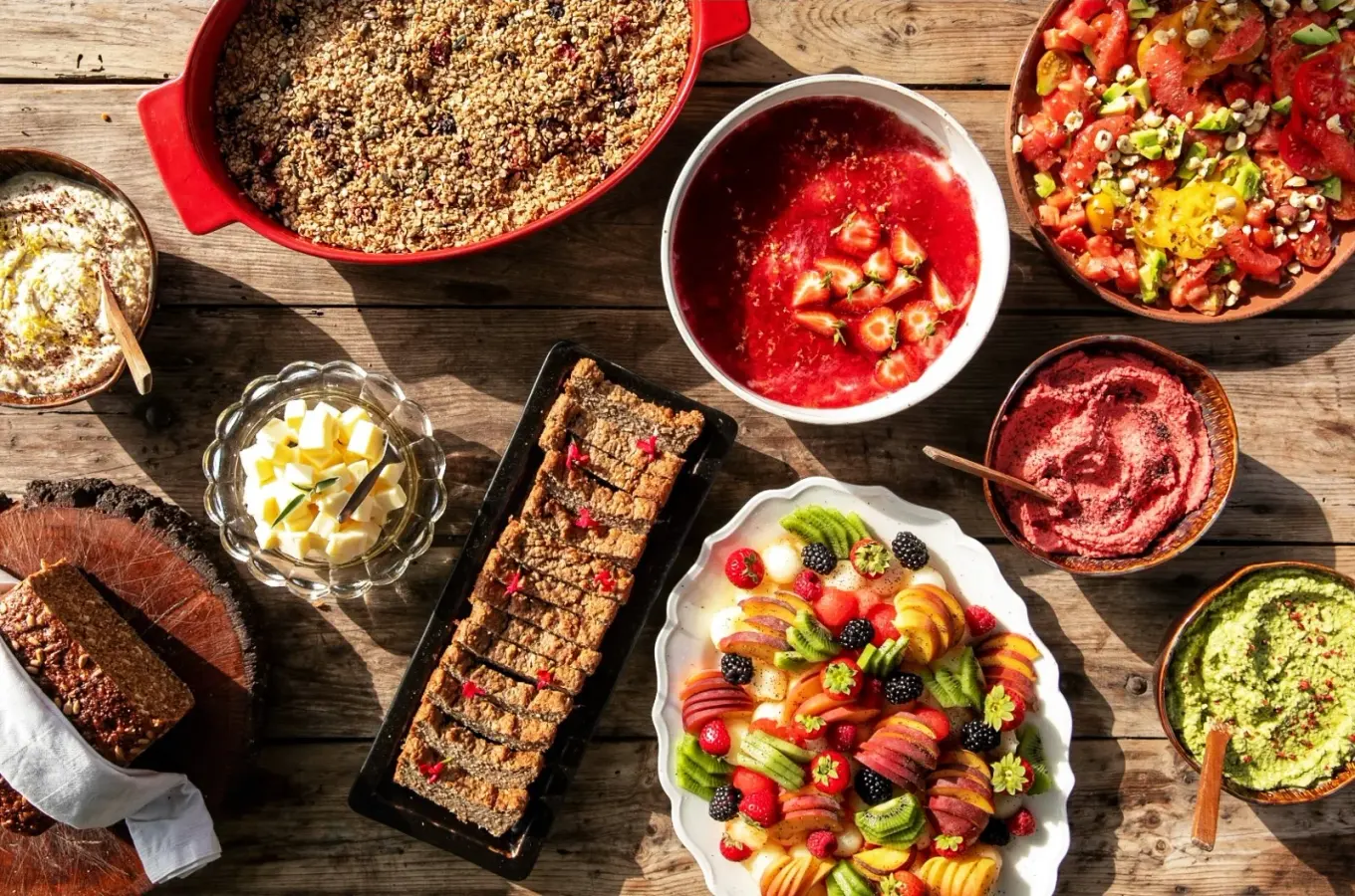 Ett generöst bord med hemlagad mat, frukt, bär, röror, sallad och bakverk på en rustik träyta.
