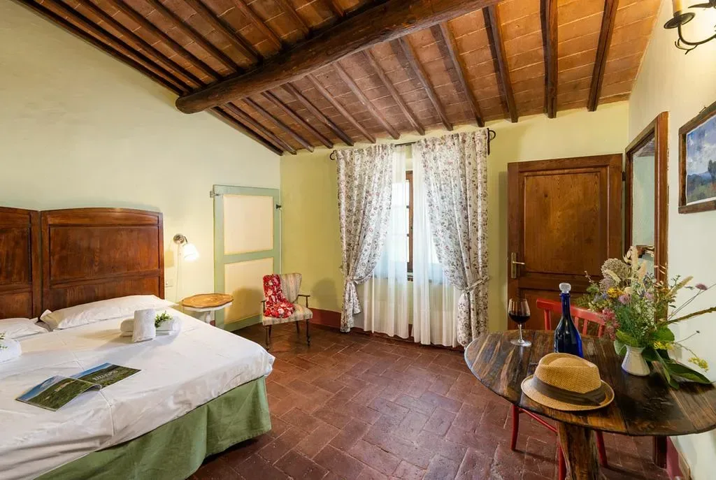 Romantiskt sovrum med varma färger och rustik inredning på konstretreat i Toscana