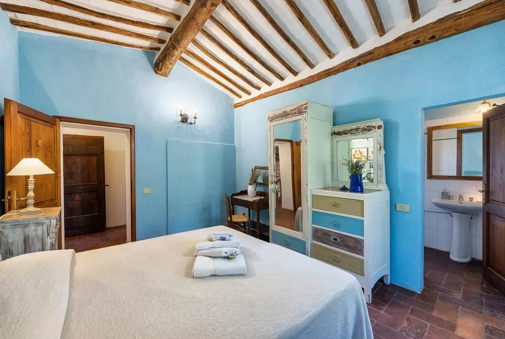Rustikt sovrum med blå väggar och traditionell toskansk inredning på konstretreat i Toscana