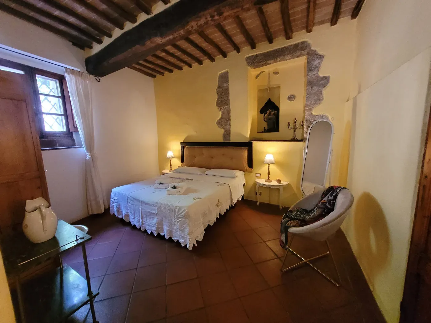 Lantligt sovrum med träbjälkar och klassisk italiensk stil på retreat i Toscana