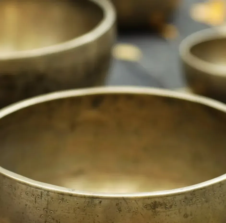 Närbild av flera tibetanska klangskålar i metall, med en stor skål i förgrunden.