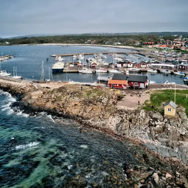 Flygvy över Torekovs kust med klippiga stränder, småbåtshamn, röda sjöbodar och bebyggelse.