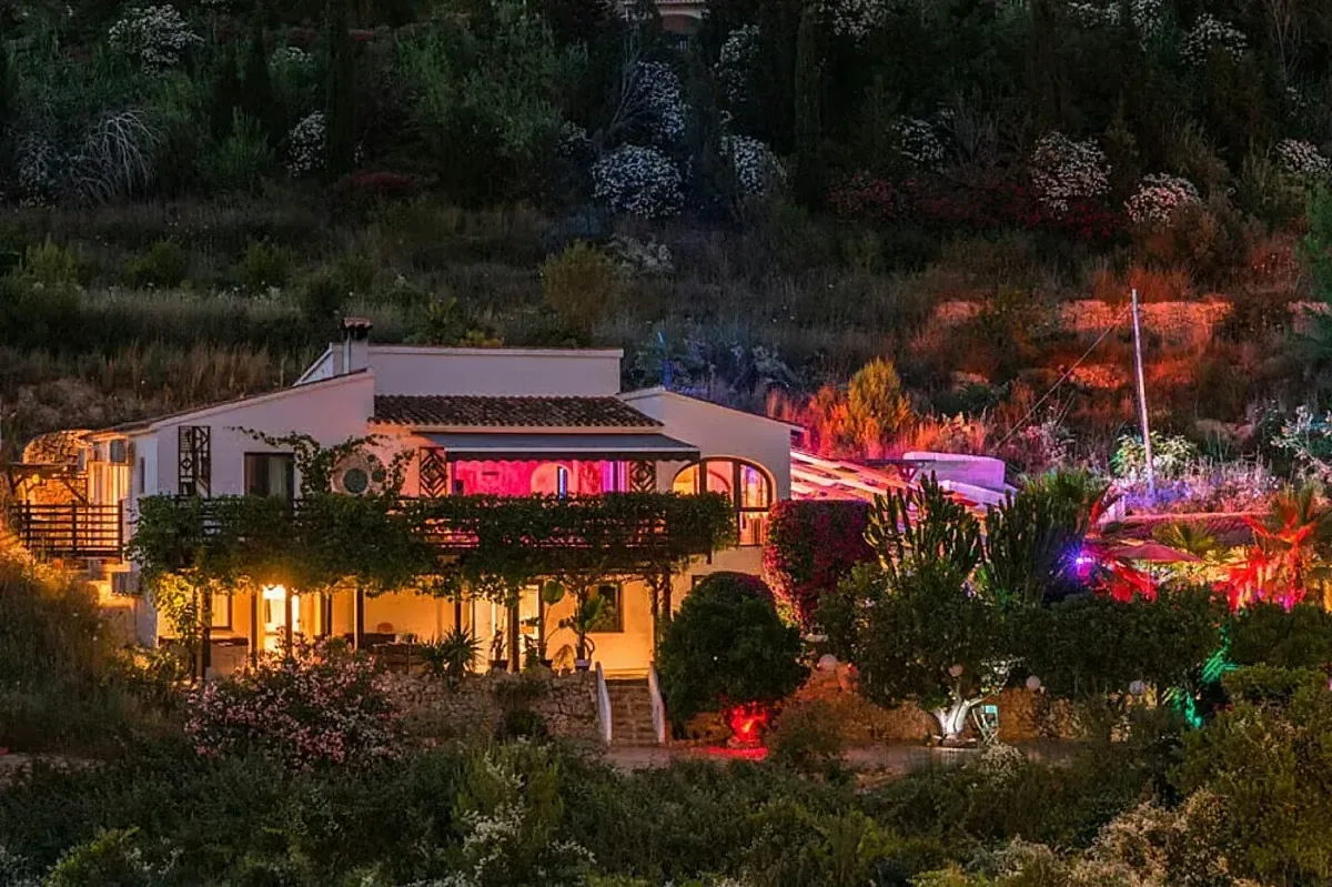 Retreatcenter omgivet av trädgård och färgstark kvällsbelysning