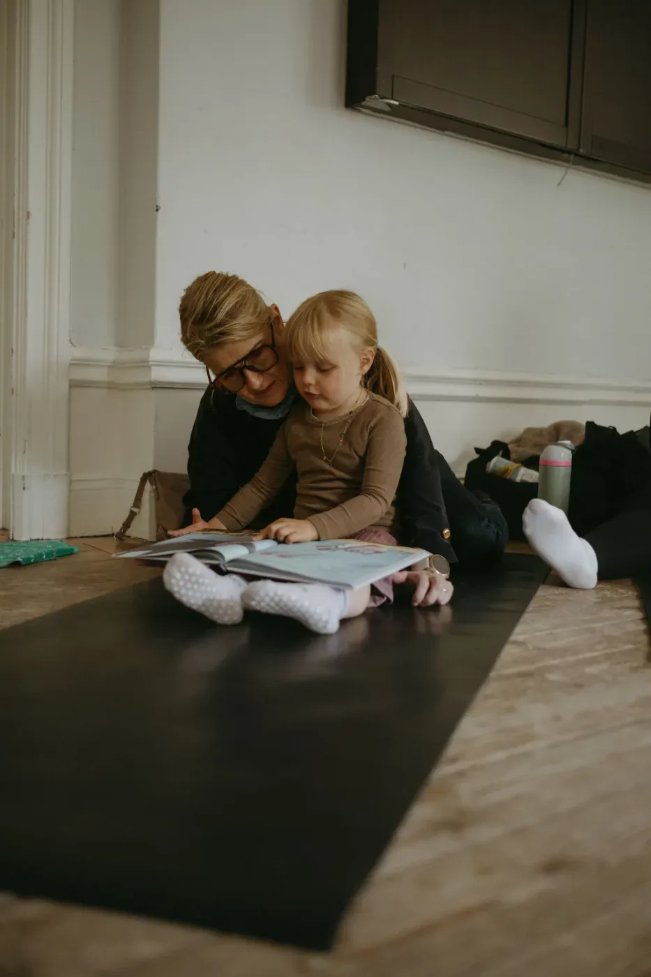 En vuxen och ett barn sitter på golvet och tittar i en bok tillsammans.