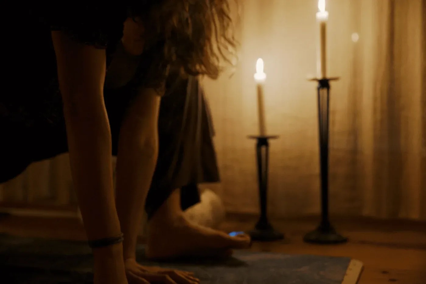 Personer utövar yoga på mattor i ett varmt, ljussatt rum med levande ljus.
