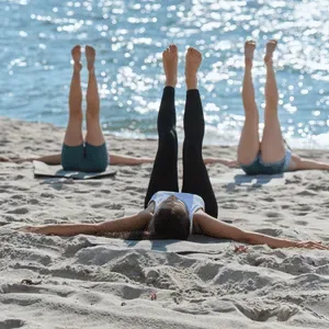 Grupp som utövar yoga på stranden under retreat
